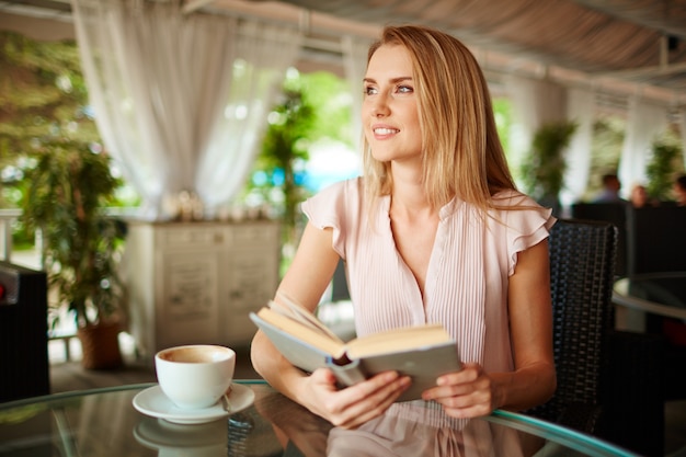 Mujer disfrutando de un libro y una taza de café