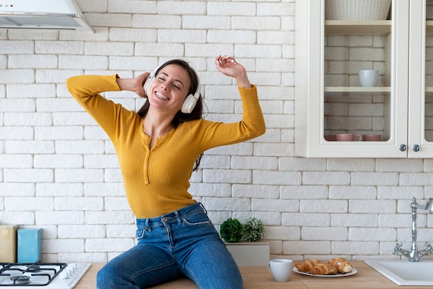 Foto gratuita mujer disfrutando de la música en la cocina.