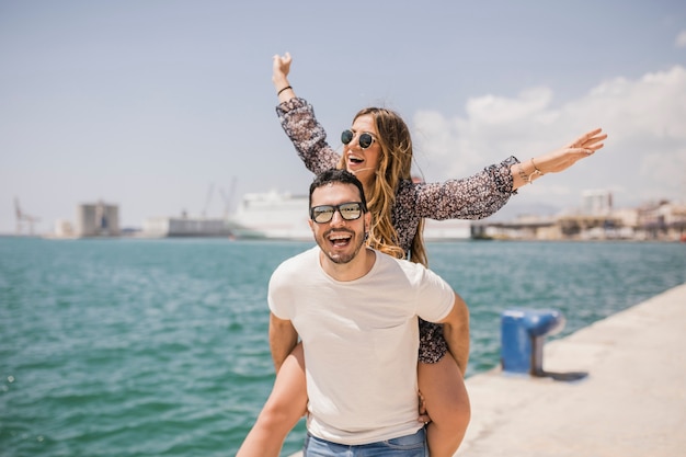 Mujer disfrutando de un paseo a cuestas en la espalda de su novio cerca del mar