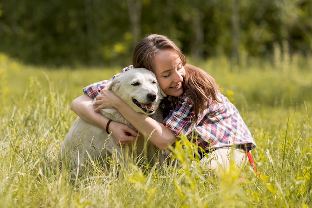 Mujer disfrutando con un perro en el campo