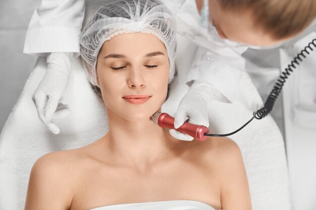 Mujer disfrutando de procedimiento de limpieza o masaje facial
