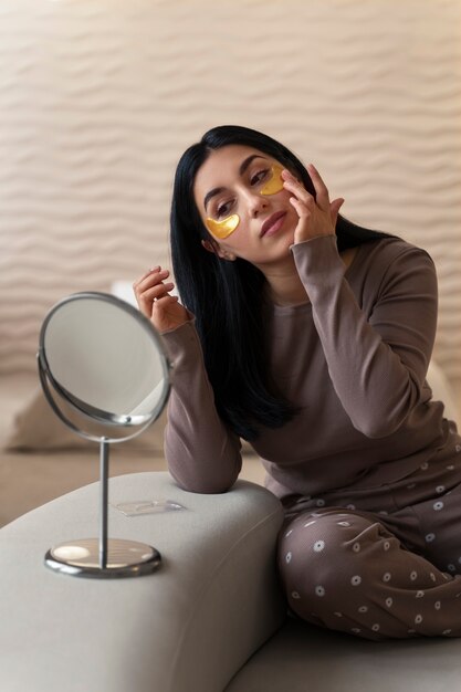 Mujer disfrutando de su rutina de belleza con parches dorados en los ojos