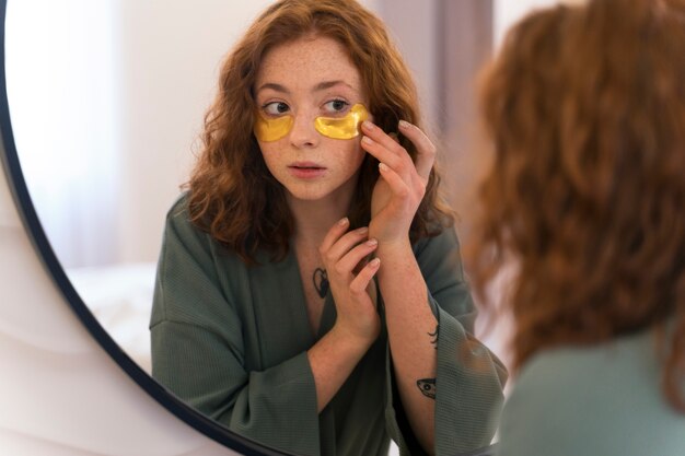 Mujer disfrutando de su rutina de belleza con parches dorados en los ojos