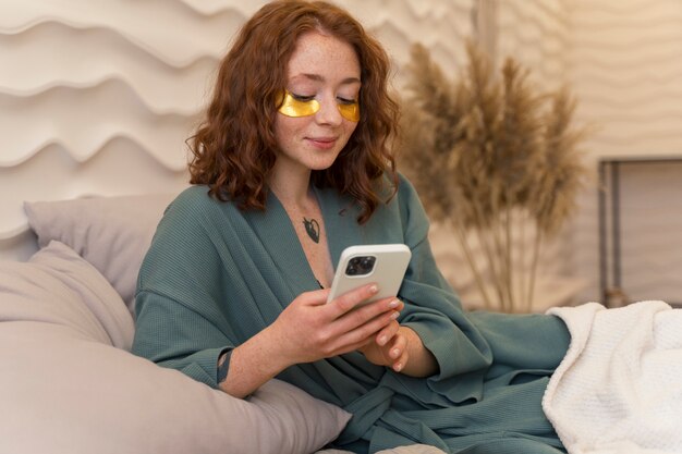 Foto gratuita mujer disfrutando de su rutina de belleza con parches dorados en los ojos