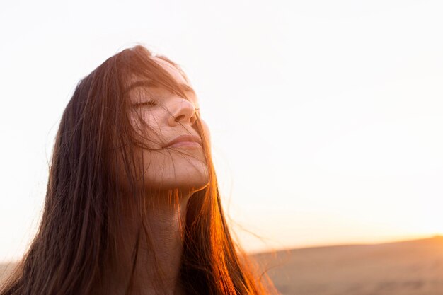 Mujer disfrutando de su tiempo en la naturaleza con puesta de sol