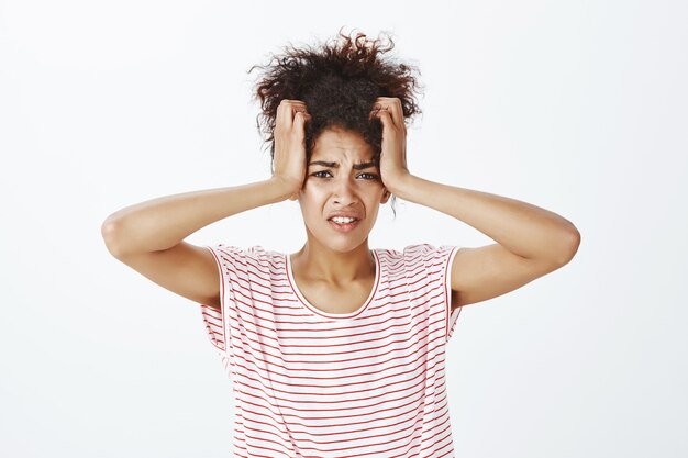 Mujer disgustada con peinado afro posando en el estudio