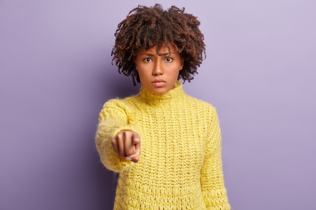 Foto gratuita mujer disgustada tiene peinado afro, culpa a alguien, apunta directamente a la cámara