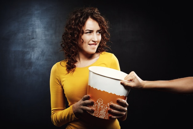 Foto gratuita mujer divertida luchando por palomitas de maíz con amigos mientras ve la película