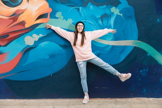 Mujer divertida de pie delante de la pared de graffiti