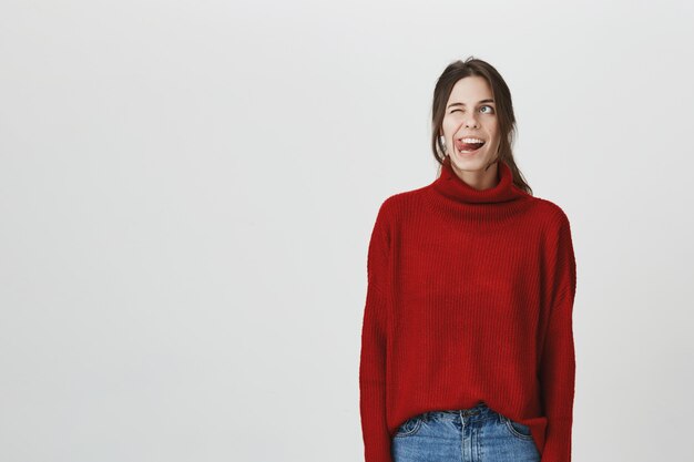 Mujer divertida sonriente que muestra la lengua, sonriente mira para arriba