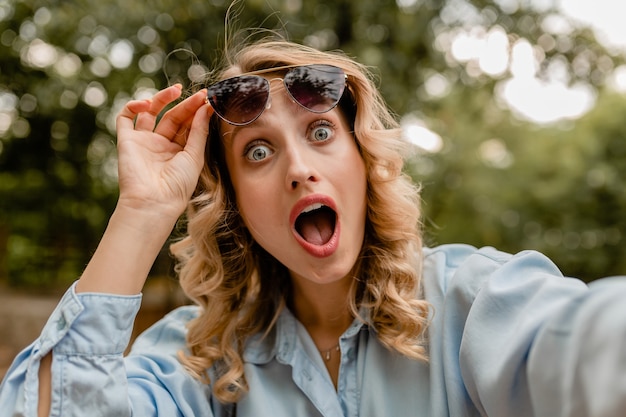 Mujer divertida sorprendida rubia atractiva en traje de verano que toma la foto del selfie en el teléfono