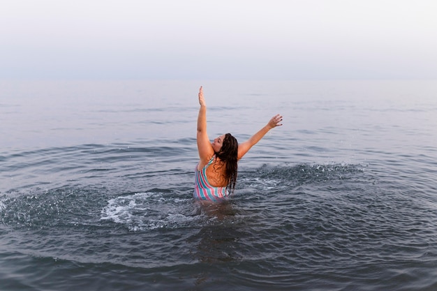Mujer divirtiéndose en el agua en la playa.