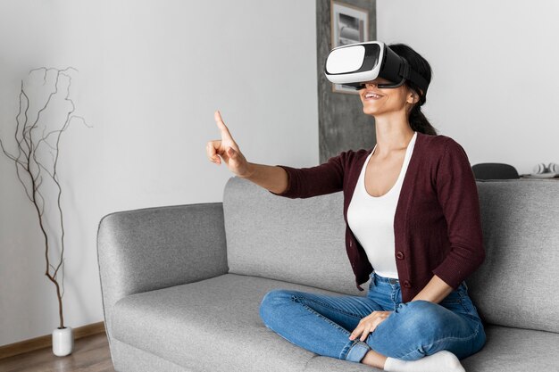 Mujer divirtiéndose en casa con casco de realidad virtual