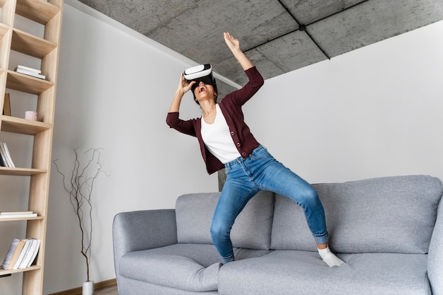 Mujer divirtiéndose en casa con casco de realidad virtual