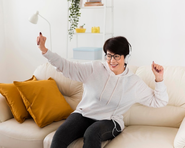 Foto gratuita mujer divirtiéndose en el sofá mientras escucha música en los auriculares