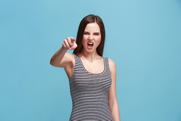 La mujer dominante te señala y te quiere retrato de primer plano de media longitud sobre fondo azul.