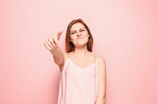 La mujer dominante te señala y te quiere, retrato de primer plano de medio cuerpo en la pared rosa