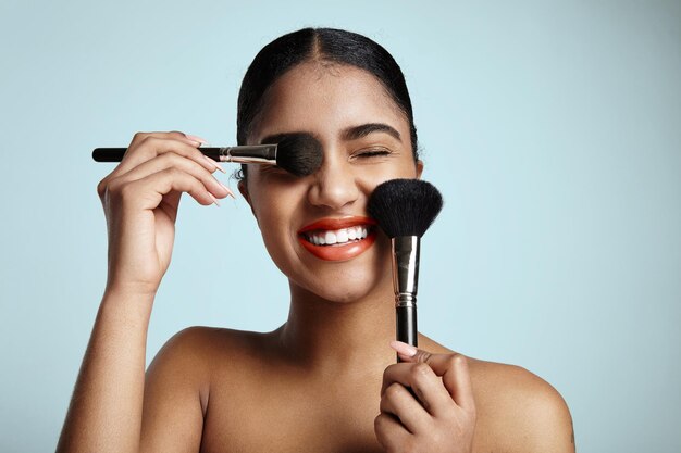 Mujer con dos cepillos cosméticos está sonriendo