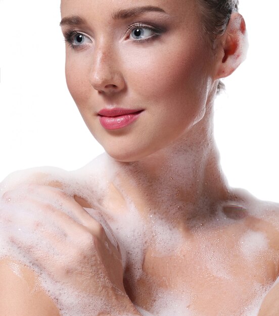 Mujer duchándose con jabón en el cuerpo y la cabeza. Concepto de higiene y cuidado de la piel.