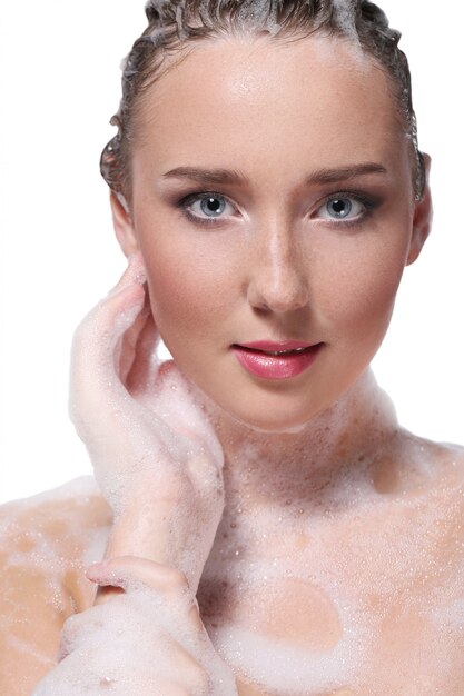 Mujer duchándose con jabón en el cuerpo y la cabeza. Concepto de higiene y cuidado de la piel.