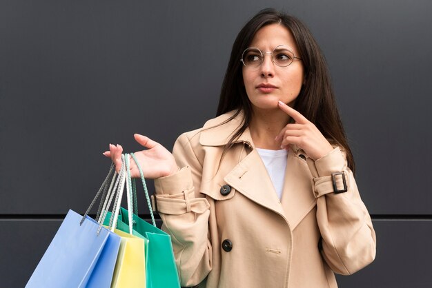 Mujer dudosa sosteniendo un montón de bolsas de la compra.