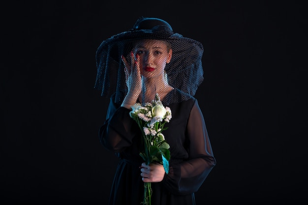 Mujer de duelo vestida de negro con flores sobre negro escritorio aislado muerte funeral