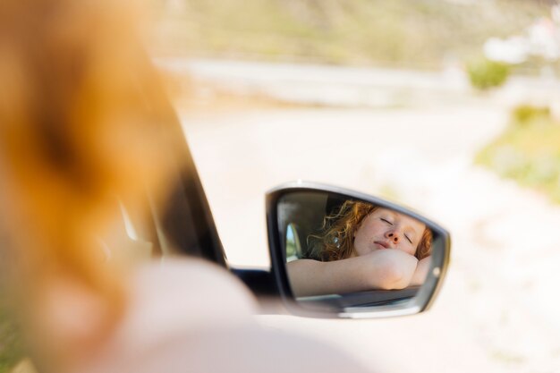 Mujer durmiendo en el espejo lateral del coche