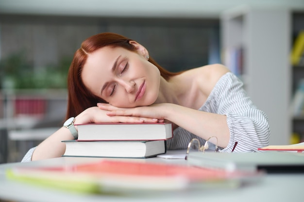 Mujer durmiendo la siesta con la cabeza sobre una pila de libros