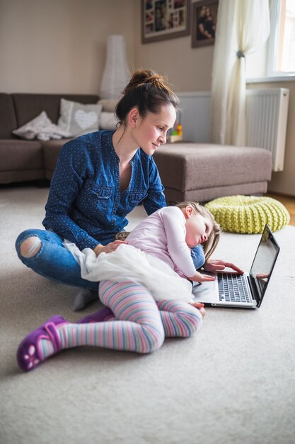 Mujer e hija mirando la pantalla del portátil