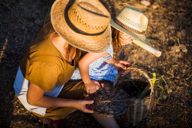 Mujer e hija mirando vegetales cosechados en la canasta