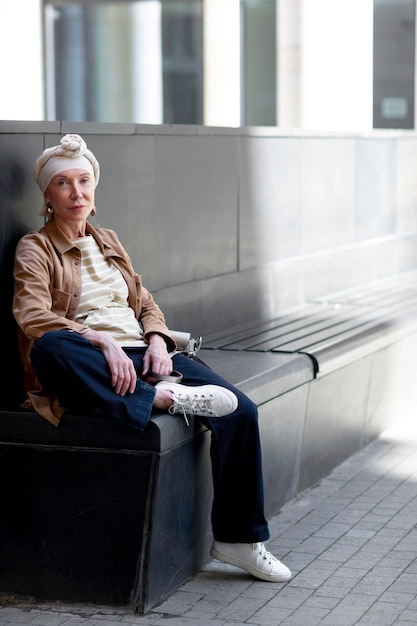 Mujer de edad al aire libre en la ciudad sentado en un banco