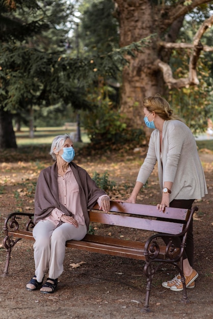 Mujer de edad avanzada con máscara médica y mujer en el hogar de ancianos