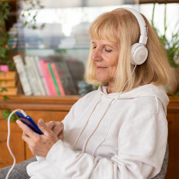 Mujer de edad disfrutando de la música en casa con auriculares