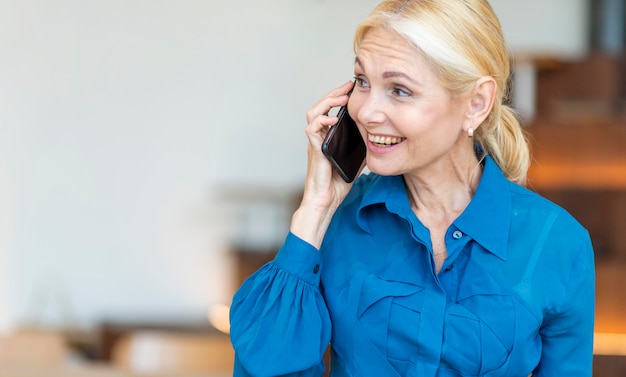 Mujer de edad hablando por teléfono mientras trabaja