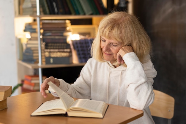 Mujer de edad leyendo un libro en casa