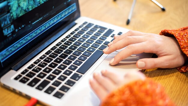 Mujer editando video en su computadora portátil. Micrófono sobre la mesa. Trabajando desde casa