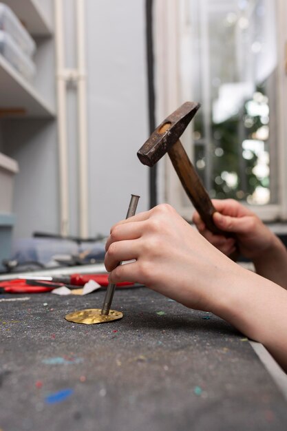 Mujer elaborando en pieza de metal dorado