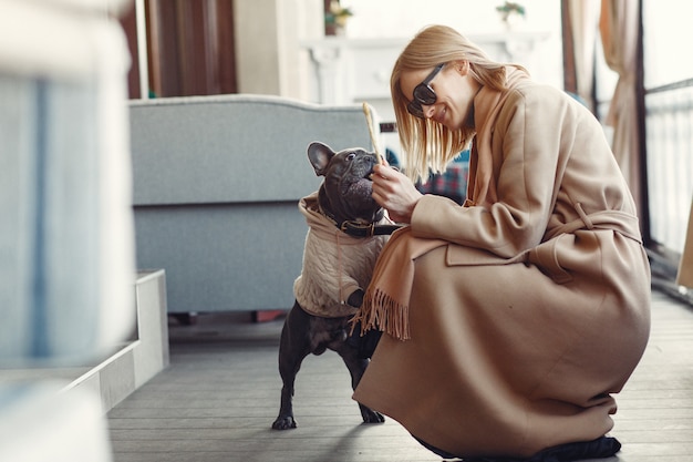 Mujer elegante con un abrigo marrón con bulldog negro