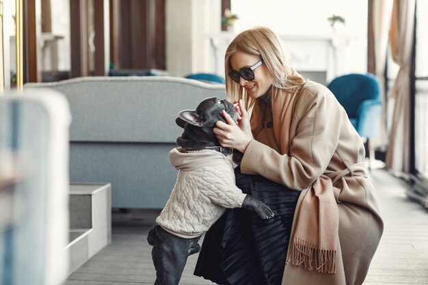 Mujer elegante con un abrigo marrón con bulldog negro