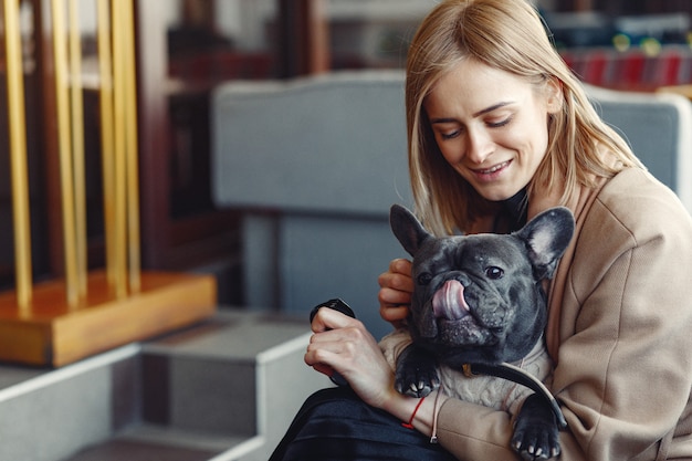 Mujer elegante con un abrigo marrón con bulldog negro