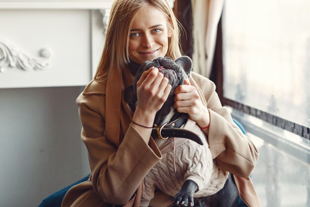 Mujer elegante con un abrigo marrón con bulldog negro