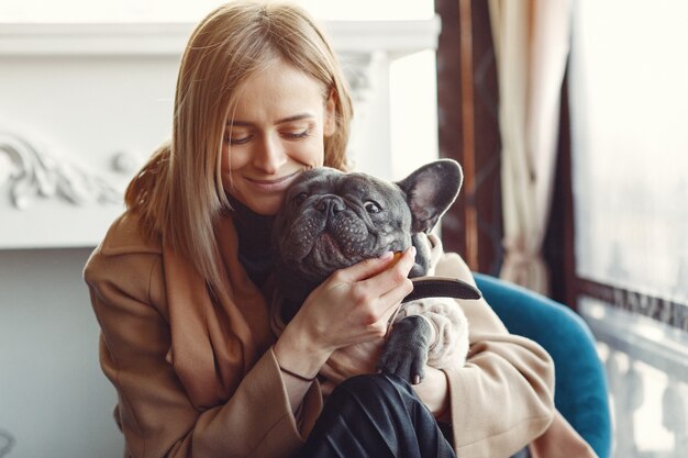 Mujer elegante con un abrigo marrón con bulldog negro