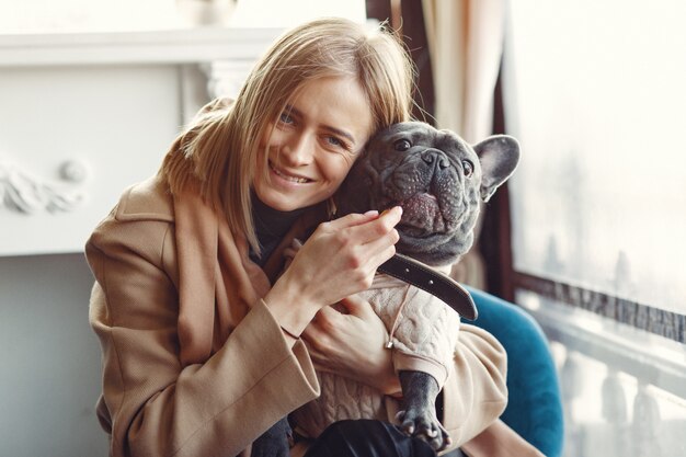 Mujer elegante con un abrigo marrón con bulldog negro