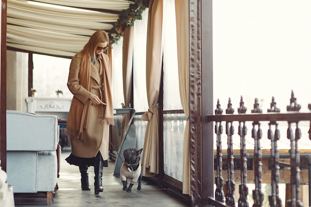 Mujer elegante con un abrigo marrón con bulldog negro