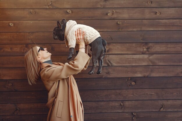 Mujer elegante con un abrigo marrón con bulldog negro