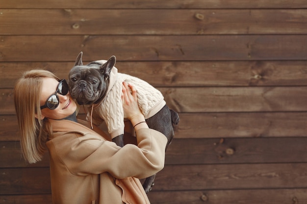 Foto gratuita mujer elegante con un abrigo marrón con bulldog negro