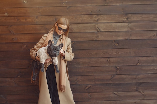 Mujer elegante con un abrigo marrón con bulldog negro