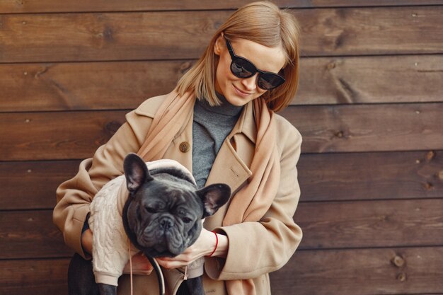 Mujer elegante con un abrigo marrón con bulldog negro