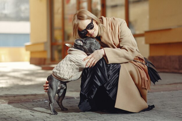 Mujer elegante con un abrigo marrón con bulldog negro