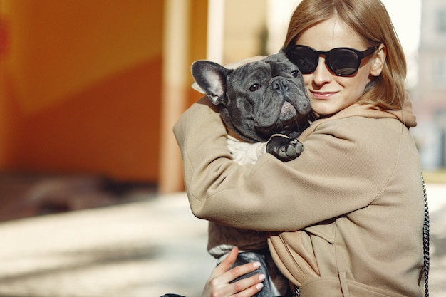 Mujer elegante con un abrigo marrón con bulldog negro